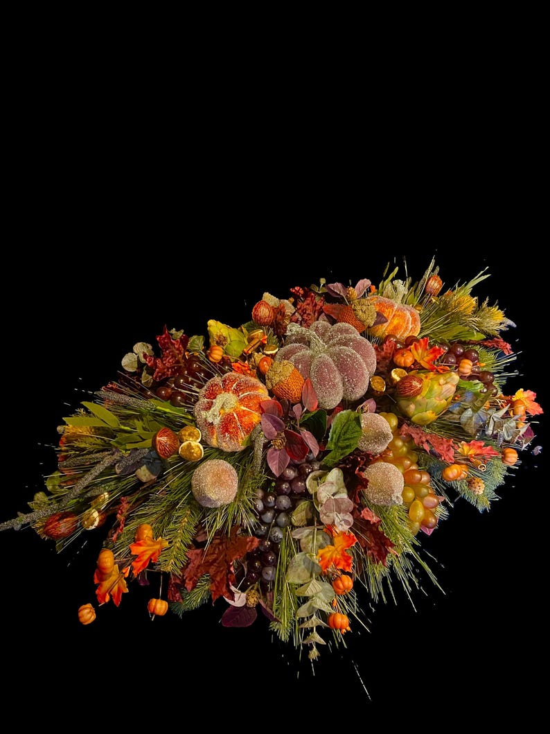 Puede incluir: Un vibrante arreglo oto&ntilde;al con calabazas, uvas y follaje de oto&ntilde;o. La exhibici&oacute;n incluye elementos naranjas, morados y verdes, creando una composici&oacute;n festiva y colorida sobre un fondo negro.