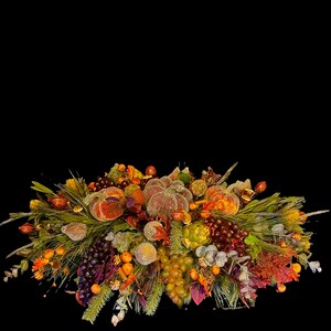 Puede incluir: Un centro de mesa con tem&aacute;tica oto&ntilde;al con calabazas, uvas y varios follajes. El arreglo presenta elementos naranjas, marrones y verdes, creando una exhibici&oacute;n festiva y decorativa. El centro de mesa est&aacute; sobre un fondo negro.
