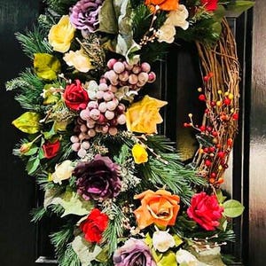May include: A lush green wreath with a variety of colorful silk flowers, including purple, red, orange, yellow, and white. The wreath is decorated with green leaves and berries.