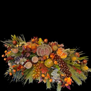 Puede incluir: Un centro de mesa con tem&aacute;tica oto&ntilde;al con calabazas, uvas y follaje variado. El arreglo presenta elementos naranjas, marrones y verdes, incluyendo agujas de pino, bayas y calabazas decorativas. El centro de mesa est&aacute; sobre un fondo negro.