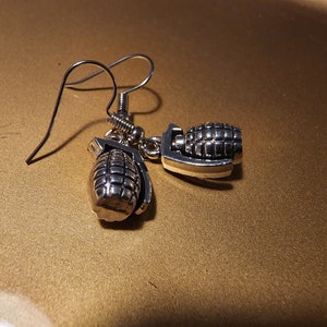 May include: A pair of silver earrings shaped like hand grenades.