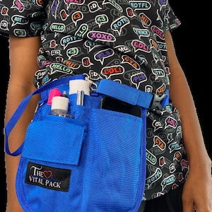 May include: A blue medical utility belt with multiple pockets and a strap. The belt has a label that says "The Vital Pack" with a heart symbol. The belt is worn by a person with a black shirt with a pattern of speech bubbles with various words and phrases.