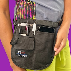 May include: Black medical utility belt with multiple pockets and a cell phone holder. The belt has a logo that says "The Vital Pack" with a heart and EKG line.