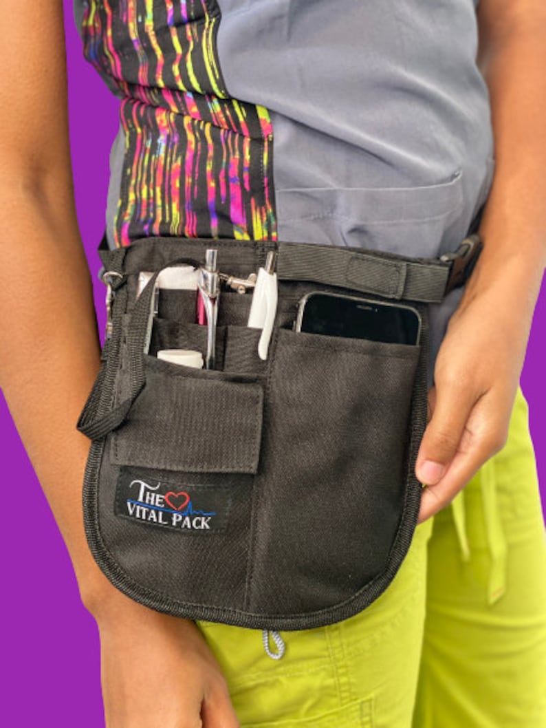 May include: Black medical utility belt with multiple pockets and a cell phone holder. The belt has a logo that says "The Vital Pack" with a heart and EKG line.
