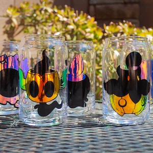 May include: Six clear glass can-shaped glasses with holographic accents and Halloween-themed designs. Each glass features a different black silhouette character with orange and yellow details, perfect for spooky season.