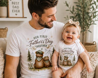 May include: White t-shirts and onesie with matching "Our First Father's Day Together" bear graphic. The adult shirt is paired with blue jeans. A baby wears a matching onesie and a beige bow headband. A framed sign reads "Best Dad Ever".
