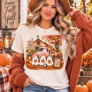 Peut inclure: Un t-shirt crème avec un motif coloré représentant un camion rose, trois fantômes portant des bonnets et un hérisson. Le dessin inclut le texte Pumpkins, Apple Cider, Hay Rides, Corn Maze, Farm Fresh Fun et Meet Me at the Pumpkin Patch.