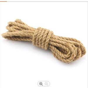 May include: A close-up of a thick, natural brown jute rope coiled on a white background.
