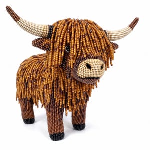 May include: A handcrafted figurine of a Highland cow constructed entirely from small, multi-colored beads. The cow features long, shaggy brown and tan beaded fringe, cream-colored horns, and a light-colored muzzle with black bead accents.