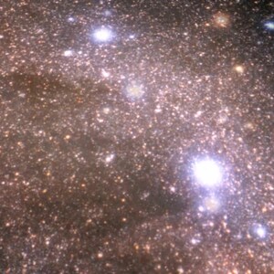 Puede incluir: Una vista cercana de una galaxia llena de estrellas con algunas estrellas brillantes en el centro. La galaxia es una masa giratoria de luz y oscuridad, con un ligero tono rosado.