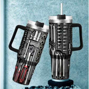 May include: Two stainless steel travel mugs with black handles and lids. The mugs are decorated with a tool set design, featuring wrenches, sockets, and screwdrivers. One mug has a straw. The mugs are on a light blue background.