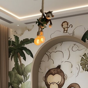 Puede incluir: Una cama infantil verde y marrón con un mural de temática de selva con monos y palmeras. La cama tiene un edredón estampado en verde y blanco y varios monos de peluche.