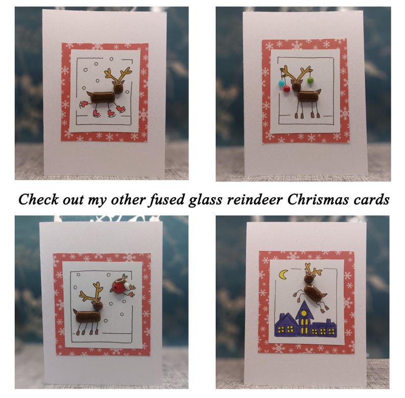 May include: Four white greeting cards featuring fused glass reindeer designs. Each card has a red border with white snowflakes. The reindeer are depicted in various scenes including ice skating, holding ornaments, with a bird, and flying over houses.