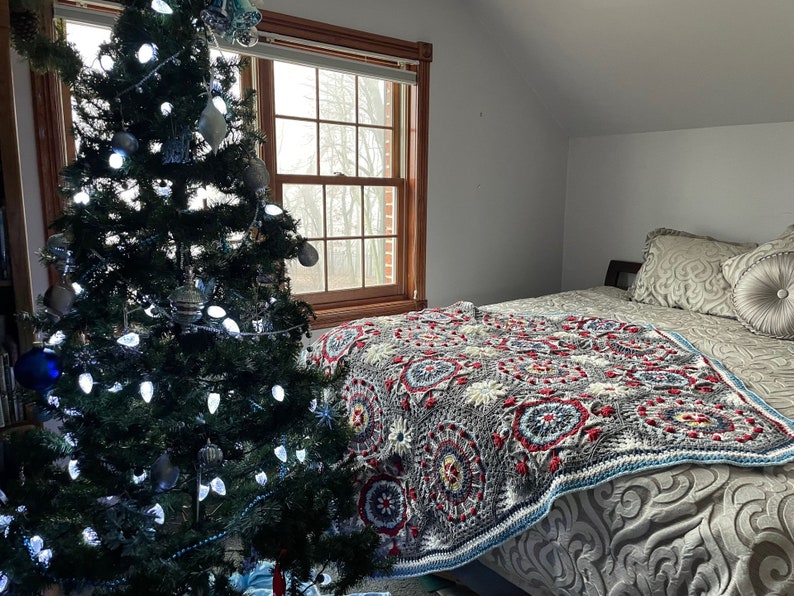 K&ouml;nnte beinhalten: Ein Schlafzimmer mit einem Weihnachtsbaum, der mit wei&szlig;en Lichtern geschm&uuml;ckt ist, und einem Bett mit einer bunten H&auml;keldecke.