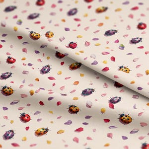 May include: A fabric with a repeating pattern of watercolor ladybugs in red, orange, yellow, and purple. The ladybugs are scattered among colorful petals on a cream-colored background.