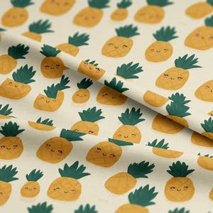 Peut inclure: Tissu crème avec un motif répété d'ananas jaunes souriants avec des dessus verts. Certains ananas sont entiers, et d'autres sont coupés. Le tissu est plié dans l'image.