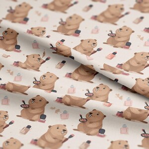 Peut inclure: Motif répétitif sur tissu avec des castors de dessin animé se maquillant. Les castors bruns aux yeux noirs sont entourés d'articles de maquillage roses et bruns, dont du rouge à lèvres et du vernis à ongles.