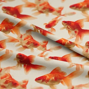 May include: A repeating pattern of orange and white goldfish on a cream background. The goldfish are in different sizes and positions, creating a dynamic design. The fabric appears soft and suitable for various applications. The goldfish are in various sizes and positions.