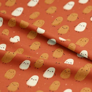 May include: A fabric featuring a repeating pattern of cartoon potatoes in shades of brown and white, each with a smiling face and small arms and legs. The background is a solid reddish-orange colour.