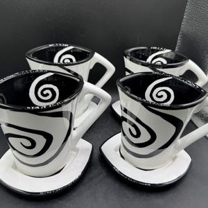 May include: A set of three ceramic mugs with a speckled, matte finish. The mugs are in shades of cream, light gray, and dark gray. Each mug has a simple, minimalist design and a rounded handle. The mugs are stacked on top of each other.