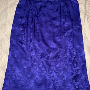 Peut inclure: Une jupe bleu roi, arrivant au genou, orn&eacute;e d'un motif floral. La jupe est faite d'un tissu brillant et soyeux. Le motif floral est d'une nuance de bleu plus fonc&eacute;e, cr&eacute;ant un contraste subtil. La jupe a un design simple et classique.