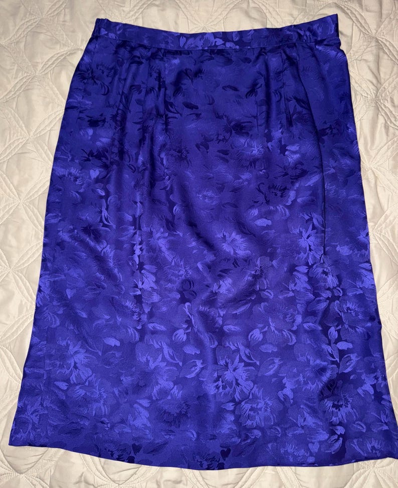Peut inclure: Une jupe bleu roi, arrivant au genou, orn&eacute;e d'un motif floral. La jupe est faite d'un tissu brillant et soyeux. Le motif floral est d'une nuance de bleu plus fonc&eacute;e, cr&eacute;ant un contraste subtil. La jupe a un design simple et classique.