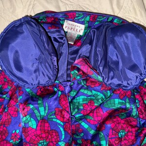 Peut inclure: Veste vintage Adrianna Papell &agrave; motifs floraux vibrants. La veste pr&eacute;sente une base violet fonc&eacute; avec de grands motifs floraux roses et verts. Le col et la doublure sont bleu roi uni. La veste a une fermeture boutonn&eacute;e.