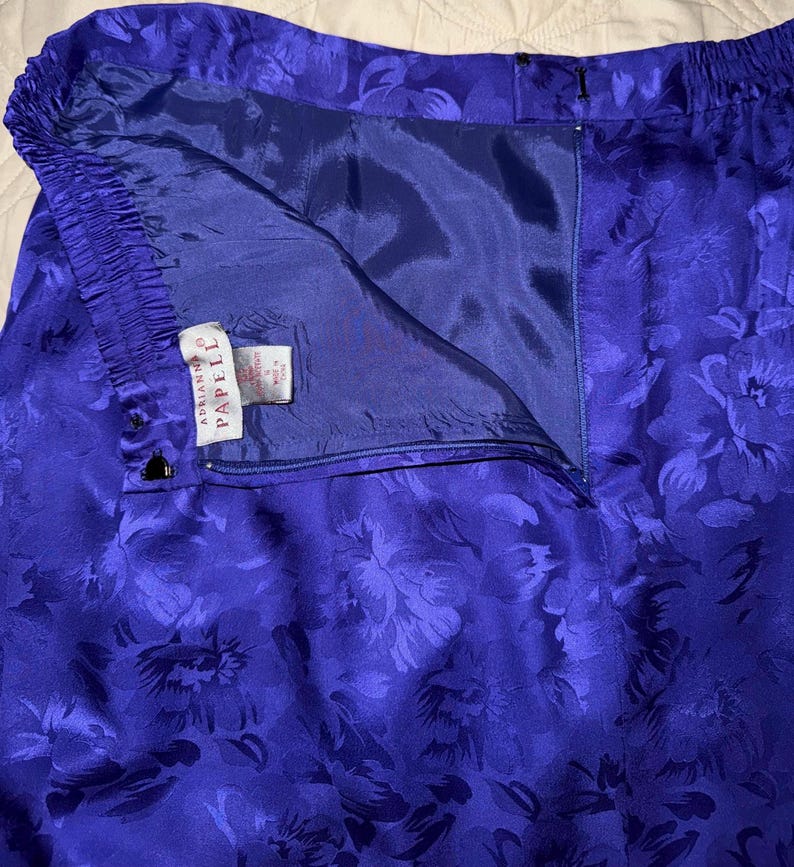 Peut inclure: Gros plan sur un pantalon bleu vif &agrave; motif floral. Le pantalon a une taille &eacute;lastique et une fermeture &eacute;clair. L'&eacute;tiquette indique "Adrianna Papell". Le tissu a un aspect soyeux.