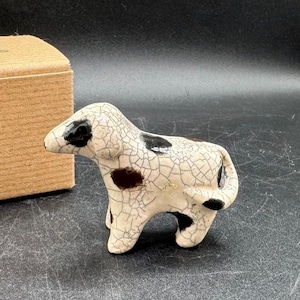 Könnte beinhalten: Eine kleine Keramik-Hundefigur mit weißer und schwarzer gesprenkelter Farbe. Der Hund steht auf allen vieren und hat eine craquelée-Glasur.