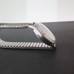 Op de afbeelding: Een zilveren polshorloge met een zilveren metalen band. De wijzerplaat van het horloge is rond en heeft een zilveren bezel.