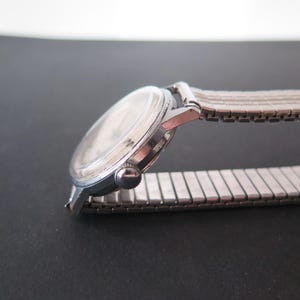 Op de afbeelding: Een zilveren polshorloge met een zilveren metalen band. Het horloge heeft een ronde wijzerplaat en een zilveren kast.