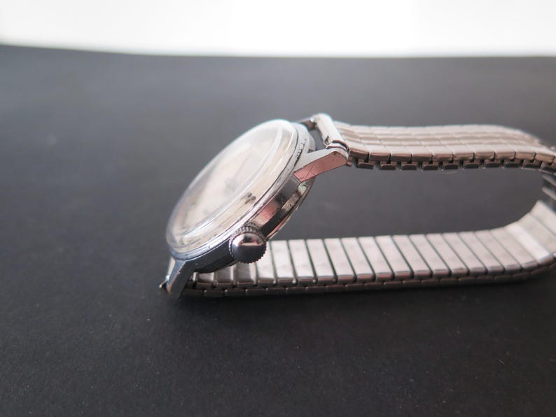 Op de afbeelding: Een zilveren polshorloge met een zilveren metalen band. Het horloge heeft een ronde wijzerplaat en een zilveren kast.