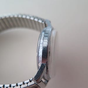 Op de afbeelding: Een zilveren polshorloge met een metalen band. De wijzerplaat van het horloge is niet zichtbaar op de afbeelding.