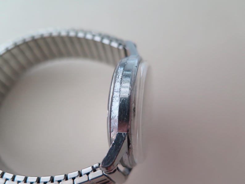 Op de afbeelding: Een zilveren polshorloge met een metalen band. De wijzerplaat van het horloge is niet zichtbaar op de afbeelding.
