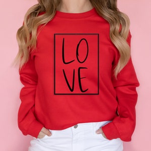 May include: Red sweatshirt with a black box and the word "LOVE" written in black inside the box.