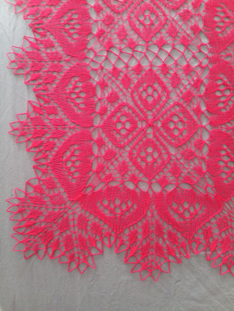 May include: A close-up of a pink crocheted lace doily with a delicate floral pattern.