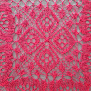 May include: A close-up of a pink crocheted lace doily with a delicate, intricate pattern.