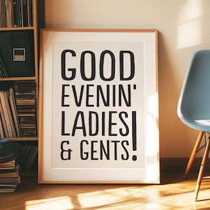 May include: A framed print with the text "GOOD EVENIN' LADIES & GENTS!" in bold black letters. The print is leaning against a wall next to a light blue chair with wooden legs. A wooden bookshelf filled with vinyl records is visible.