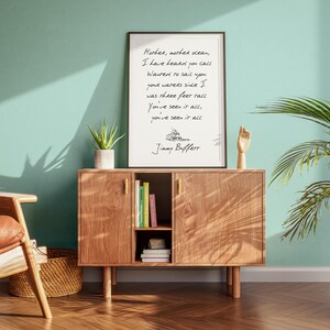 May include: A framed print with a handwritten quote by Jimmy Buffett, "Mother, mother ocean, I have heard you call, wanted to sail upon your waters since I was three feet tall. You've seen it all, you've seen it all." The print is on a wooden shelf with books and a plant.