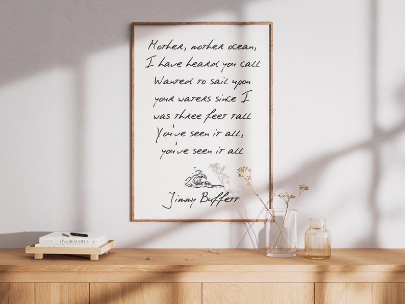 May include: A framed print with a white background and black text. The text reads "Mother, mother ocean, I have heard you call Wanted to sail upon your waters since I was three feet tall You've seen it all, you've seen it all" and is signed "Jimmy Buffett".