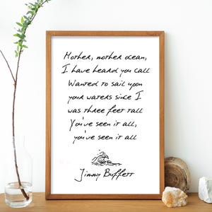 May include: A white framed print with a black and white handwritten quote by Jimmy Buffett. The quote reads: "Mother, mother ocean, I have heard you call Wanted to sail upon your waters since I was three feet tall You've seen it all, you've seen it all".