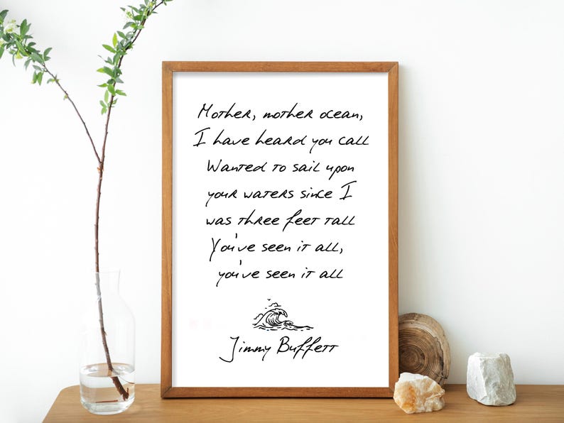 May include: A white framed print with a black and white handwritten quote by Jimmy Buffett. The quote reads: "Mother, mother ocean, I have heard you call Wanted to sail upon your waters since I was three feet tall You've seen it all, you've seen it all".