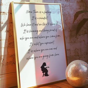 May include: A framed print with gold trim featuring the text "Home Team is a feeling. It is a mindset." and more. A silhouette of a person playing a guitar is at the bottom. A disco ball sits to the right.