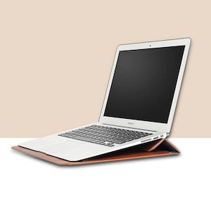 May include: A brown leather laptop case with a silver laptop inside. The laptop is open and the screen is black.