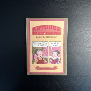 May include: A children's book titled "Arthur's Prize Reader" by Lillian Hoban. The cover features illustrations of two children in a comic strip format with the text "You can't read!" and "Oh yes I can." The book is part of the "I CAN READ Book" series.