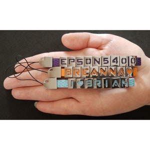 Può includere: Tre braccialetti con ciondoli argentati e cinturini in pelle colorati. I ciondoli compongono i nomi "EPSON 540", "BREANNA" e "I LOVE BRIAN".
