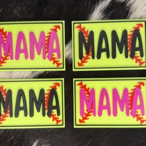 Könnte beinhalten: Vier rechteckige Aufnäher mit dem Wort "MAMA" in fetten Buchstaben. Zwei Aufnäher haben rosa Buchstaben, zwei haben schwarze Buchstaben. Jeder Aufnäher hat ein rotes Baseball-Nahtdesign und einen gelben Hintergrund.