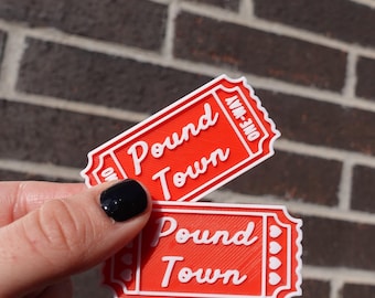 May include: Two red ticket-shaped paper crafts with white text that reads "Pound Town" and "ONE-WAY".