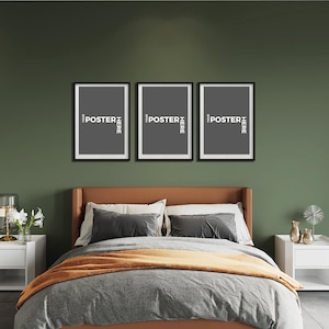 May include: Three rectangular black picture frames arranged horizontally on a dark olive green wall above a bed. Each frame contains a dark grey insert with the white text "YOUR POSTER HERE" oriented vertically along the right side of the frame.