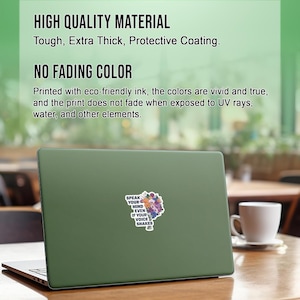 May include: A green laptop with a sticker that says "Speak your mind even if your voice shakes". The sticker has a floral design with colourful flowers and leaves.